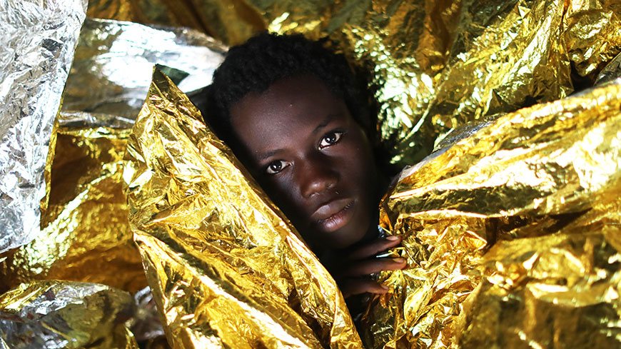 Bambino migrante della Guinea con coperte termiche a seguito di un’operazione di salvataggio in mare da parte di una ONG spagnola ©Giorgos Moutafis