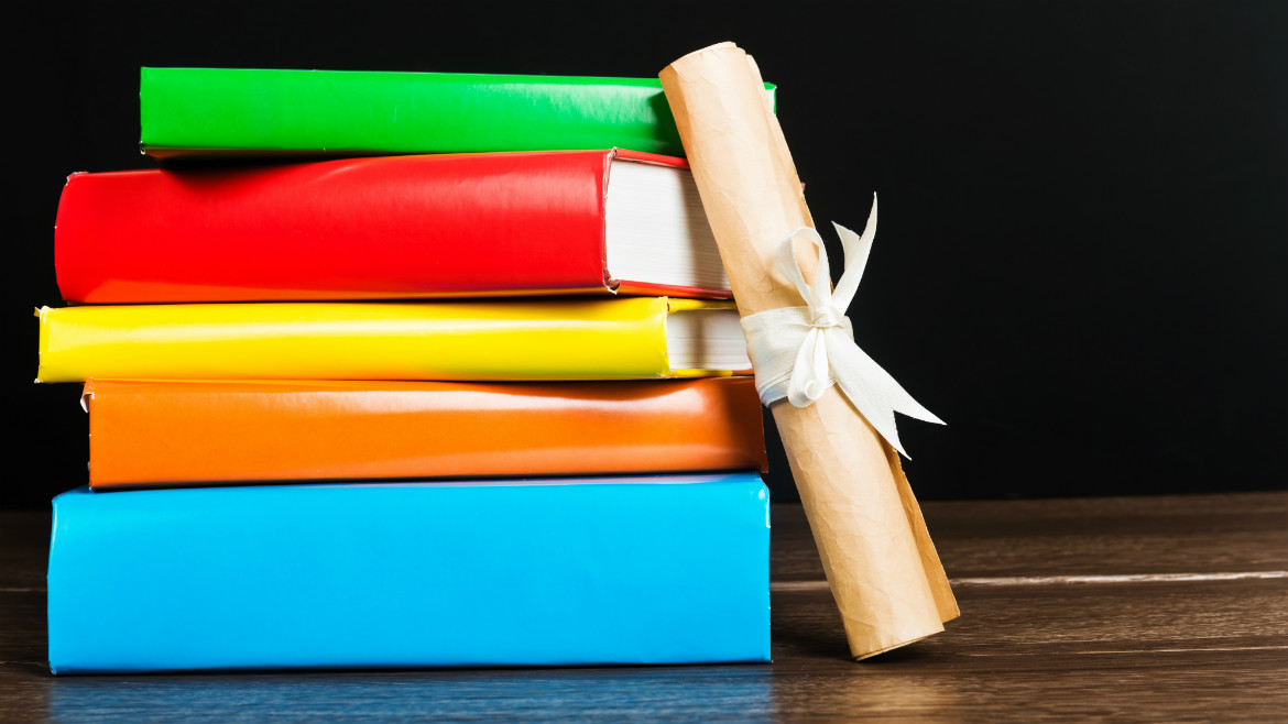 Photo of books and a diploma with a white ribbon