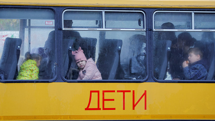 Дети, эвакуированные из подконтрольного тогда России города Херсона, ждут в автобусе, направляющемся в Крым, в городе Олешки, Херсонская область, Украина, 23 октября 2022 года. REUTERS/Александр Ермоченко