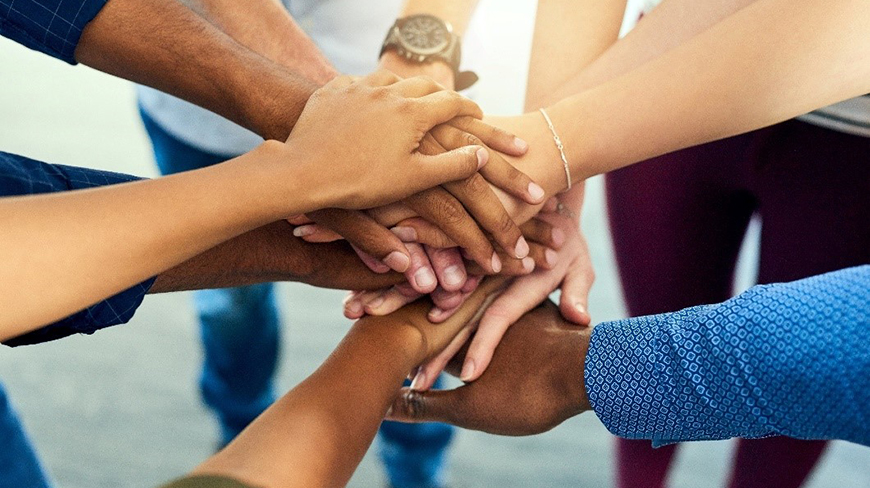Credit: Shutterstock - People in a circle place their hands on top of each other