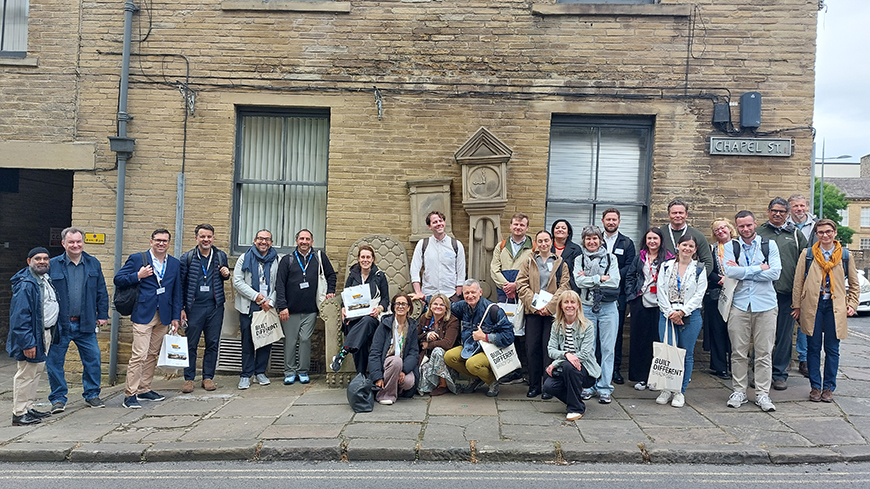 Members of the Intercultural Cities Programme on a field visit in Little Germany, Bradford, with the sculpture 'Grandad's clock and chair' by Timothy Shutter. Photo Credit: C. Charre